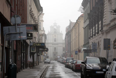 Cars on street in city against sky