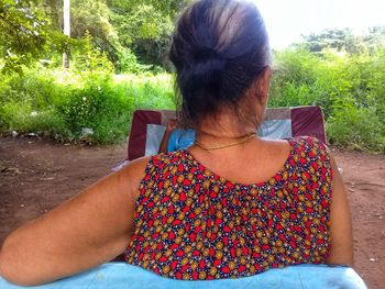 Rear view of woman sitting on plant