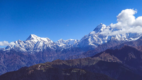 Scenic view of snowcapped mountains against blue sky