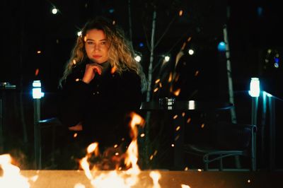 Young woman standing against illuminated fire at night