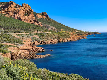 Scenic view of sea and mountains against clear blue sky