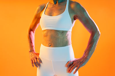 Midsection of woman standing against yellow background