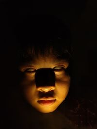 Close-up portrait of boy against black background