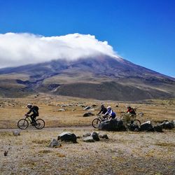 People with bicycle on mountain against sky