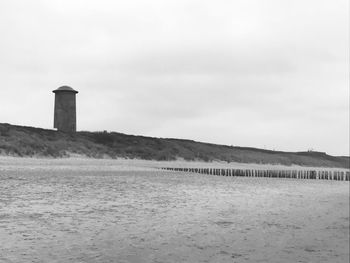 Lighthouse by sea against sky