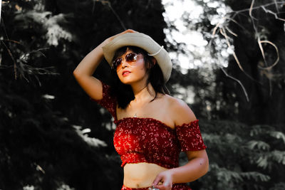 Portrait of young woman standing against tree