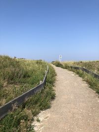 Empty road along landscape against clear sky