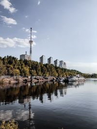 Reflection of trees in lake against sky in city