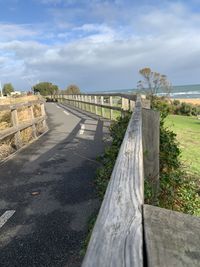 Footpath by fence against sky