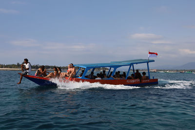 People on boat in sea against sky