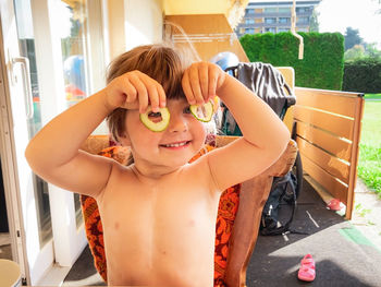 Child making a funny joke by using cucumbers as eyeglasses