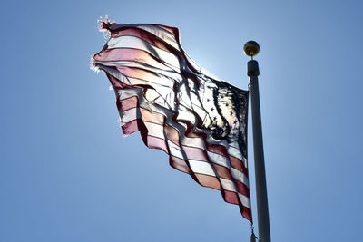 Low angle view of flags against clear blue sky