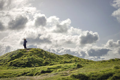 Low angle view of man standing on hill against sky