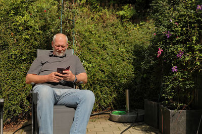 Man is checking emails on a smartphone in the garden