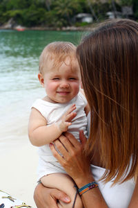 Cute mother with baby against lake