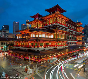 Illuminated building by street against sky at night