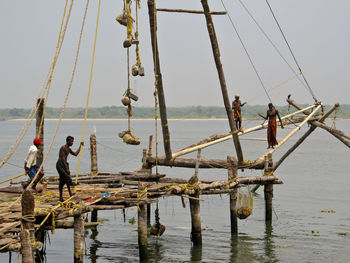 People fishing in sea against sky