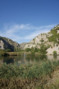 Scenic view of lake by mountains against sky