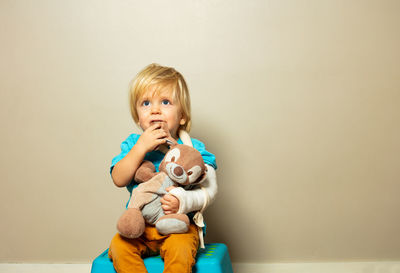 Portrait of cute girl with stuffed toy against wall