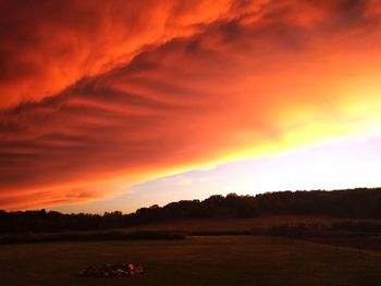 Scenic view of silhouette field against orange sky