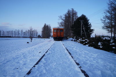 Snow covered railroad track amidst trees against sky