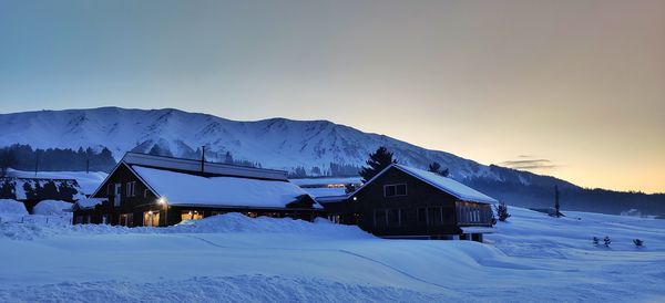 Snow covered houses and mountains against sky