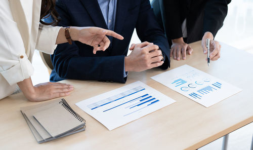 Midsection of business people working on table