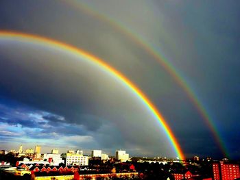 Rainbow over city against dramatic sky