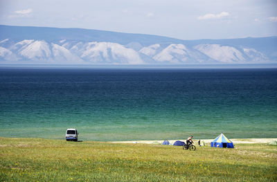 Man cycling on field against river