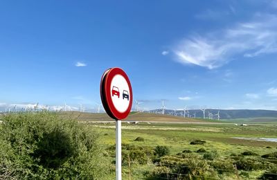 Road sign on field against sky