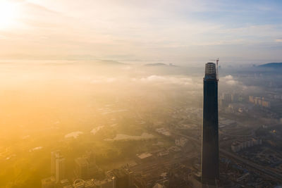 High angle view of smoke and buildings against sky during sunset