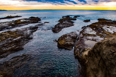 Rock formation on beach against sky during sunset