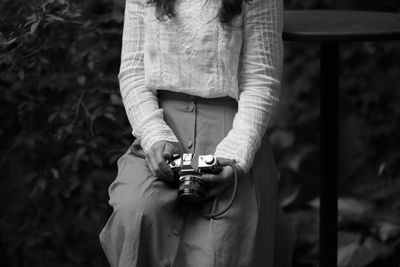 Midsection of woman holding camera