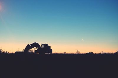 Silhouette agricultural field against clear sky during sunset