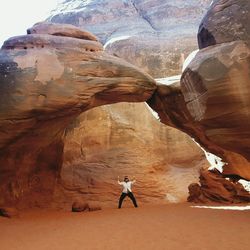Woman standing under rock formations in desert
