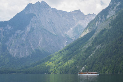 Small boat sailing on alpine lake surrounded by high mountains , konigssee, germany