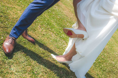Low section of bride and bridegroom standing on field