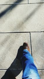 Low section of man wearing shoes and jeans while walking on paving stone