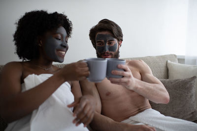 Happy diverse couple enjoying hot beverages during spa procedure