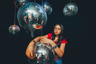 Portrait of young woman standing by disco balls in nightclub