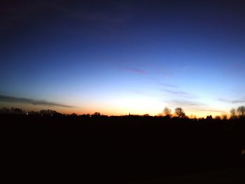 Silhouette trees on field against sky at sunset