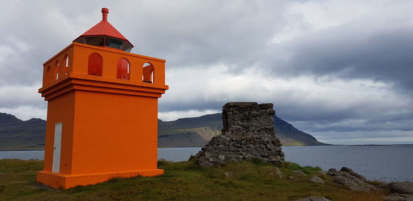 Lighthouse amidst sea and buildings against sky