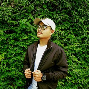 Young man wearing sunglasses standing against plants