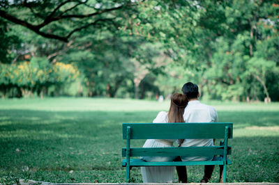 Rear view of couple sitting on bench in park