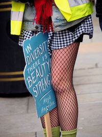 Midsection of woman holding placard while standing on street