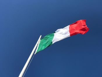 Low angle view of flag against blue sky