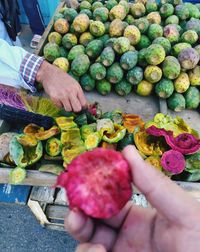 High angle view of hand holding pink fig fruits at outdoor market in morocco