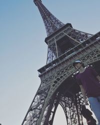 Low angle view of man standing against eiffel tower