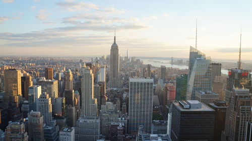 Aerial view of buildings in city against cloudy sky