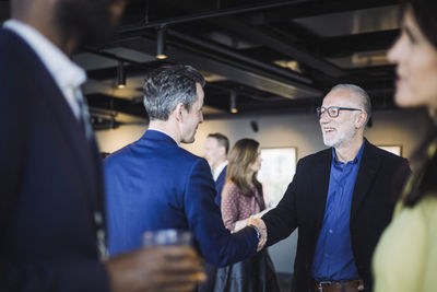 Male entrepreneurs shaking hands while standing in office